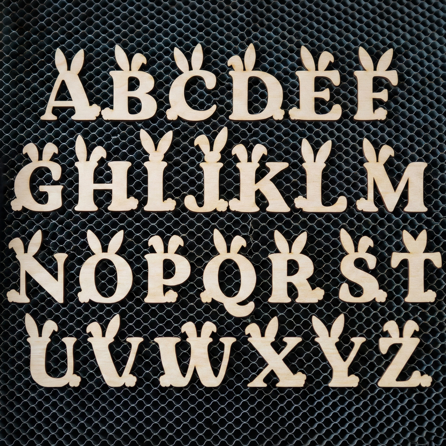 Wooden laser cut letters A to Z on a black mesh background