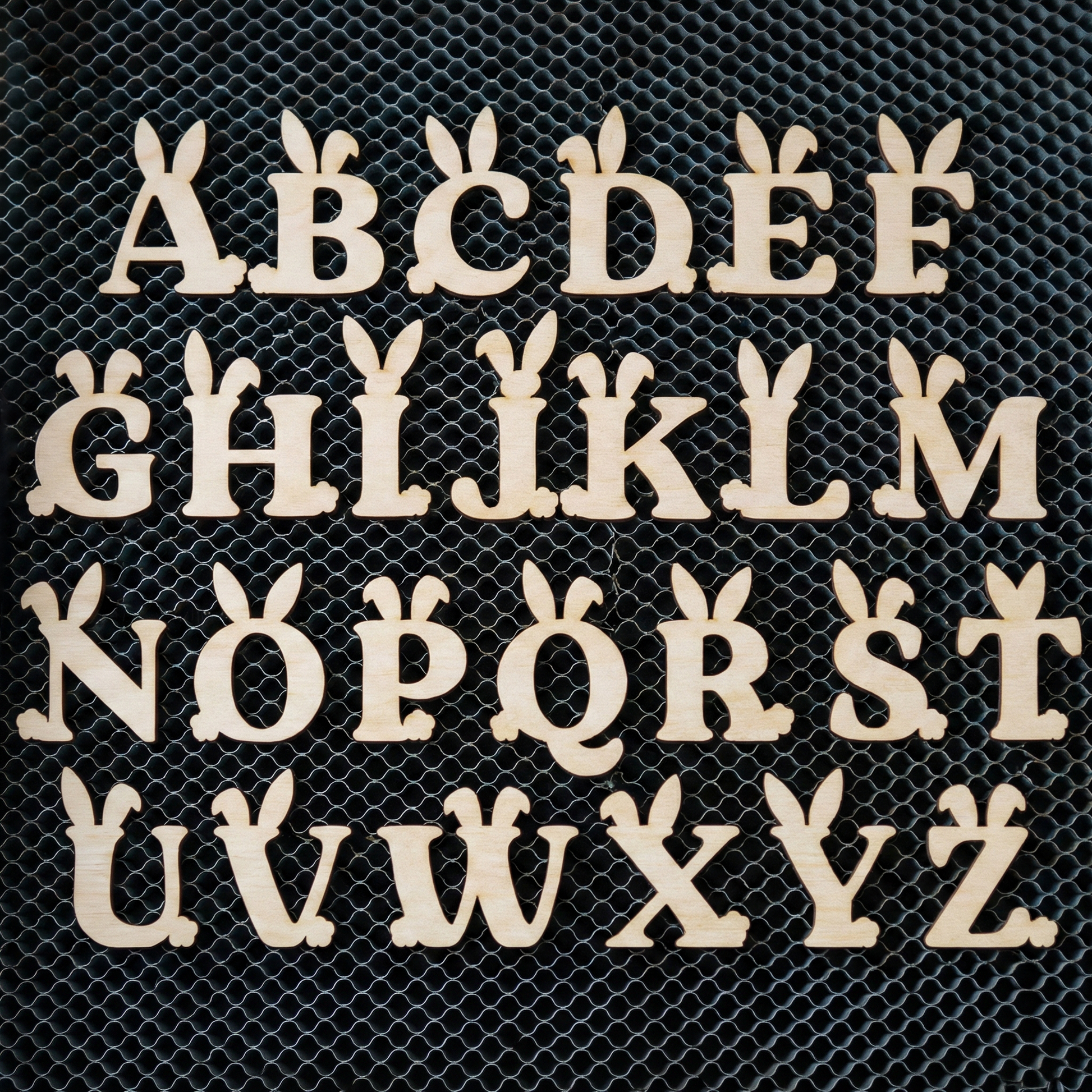 Wooden laser cut letters A to Z on a black mesh background