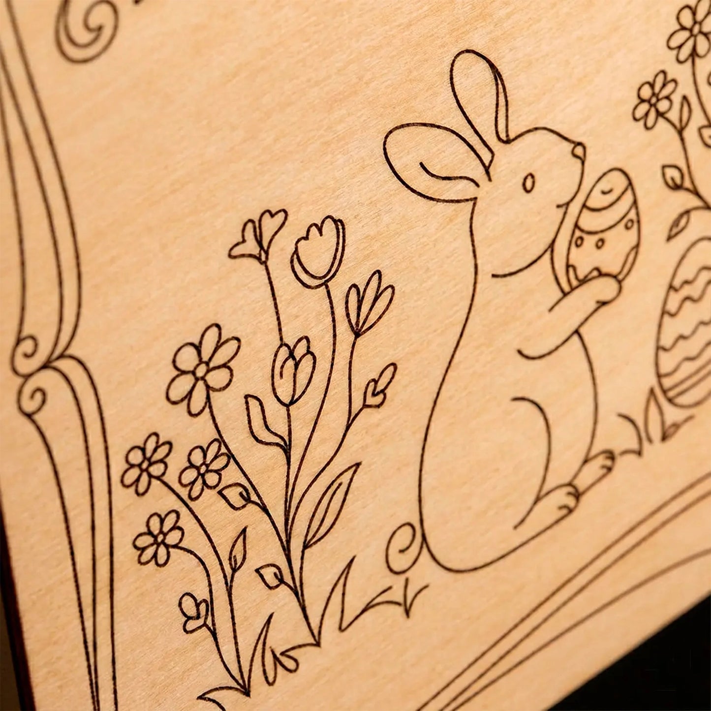 Macro detail of a laser cut plywood surface featuring an engraved Easter bunny and spring flowers design.