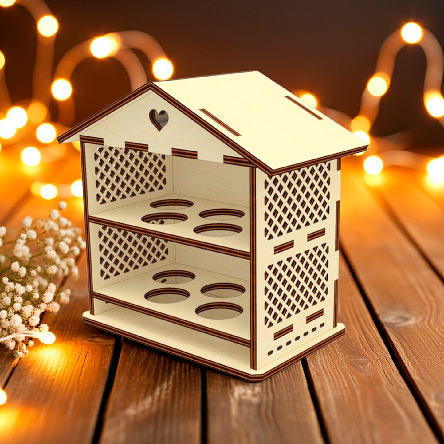 Laser cut plywood wooden house-shaped Easter egg holder with lattice sides and a heart cutout on the roof, featuring two shelves with four round slots each. It rests on a rustic wooden table with baby's breath flowers and warm, blurry fairy lights in the background.
