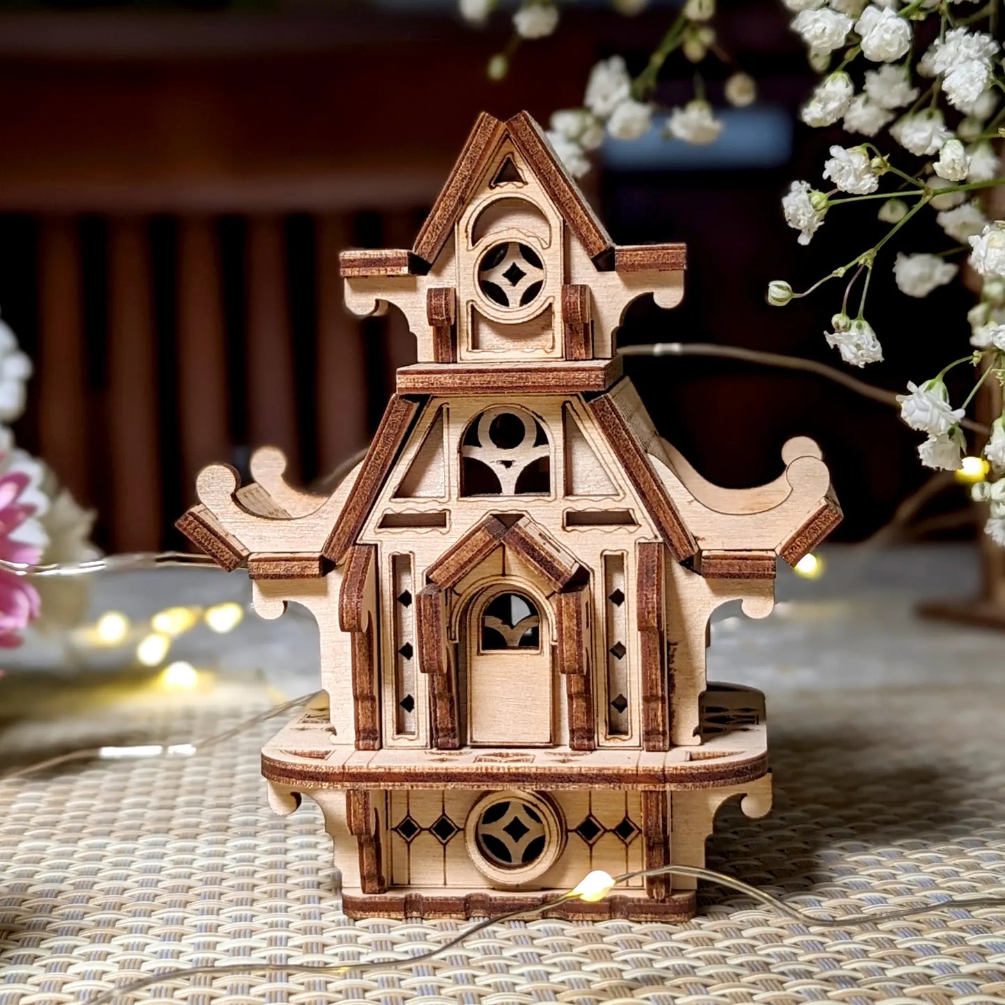 Front view of a miniature elf house made of laser cut plywood. Features detailed arched doors and windows, clean wood.