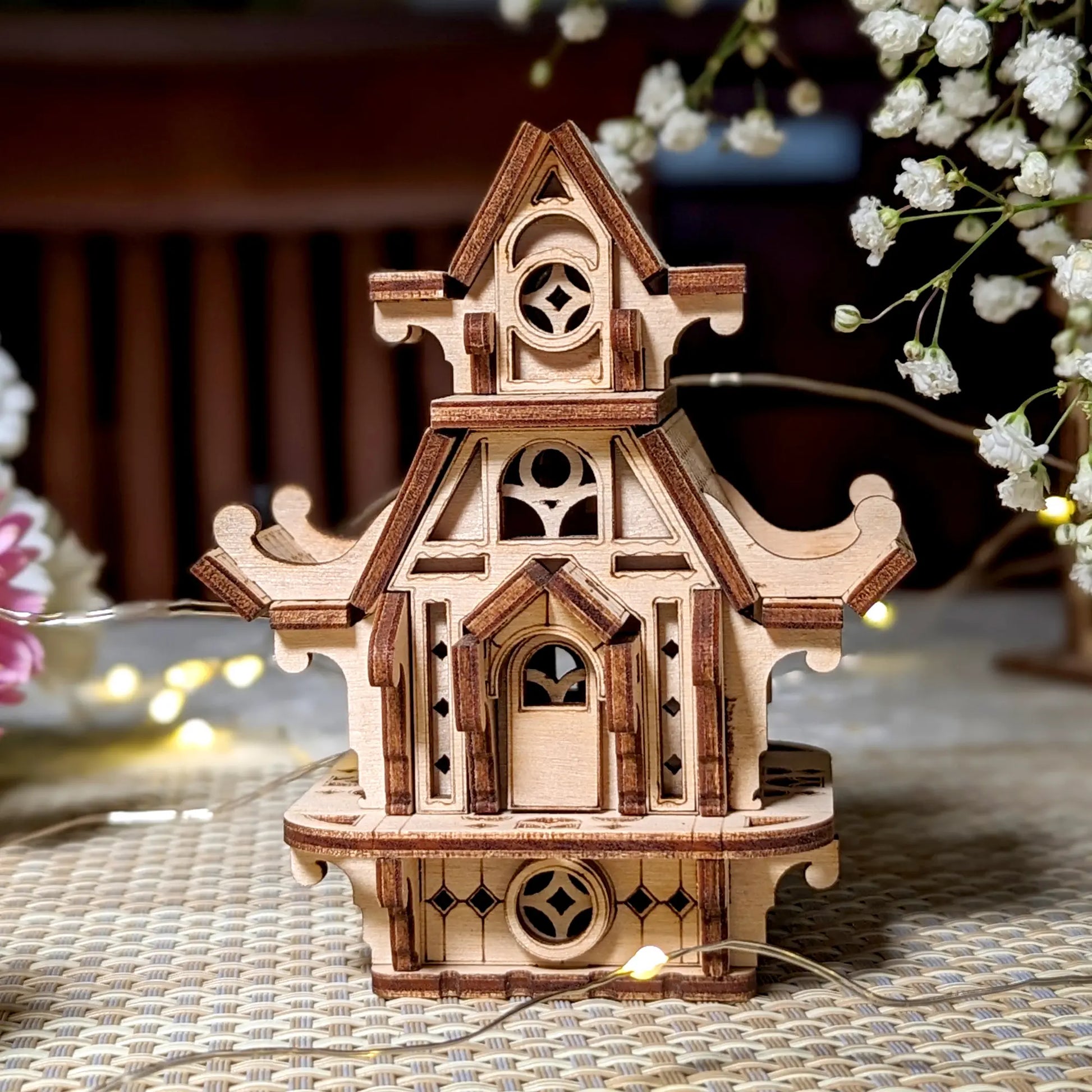 Front view of a miniature elf house made of laser cut plywood. Features detailed arched doors and windows, clean wood.