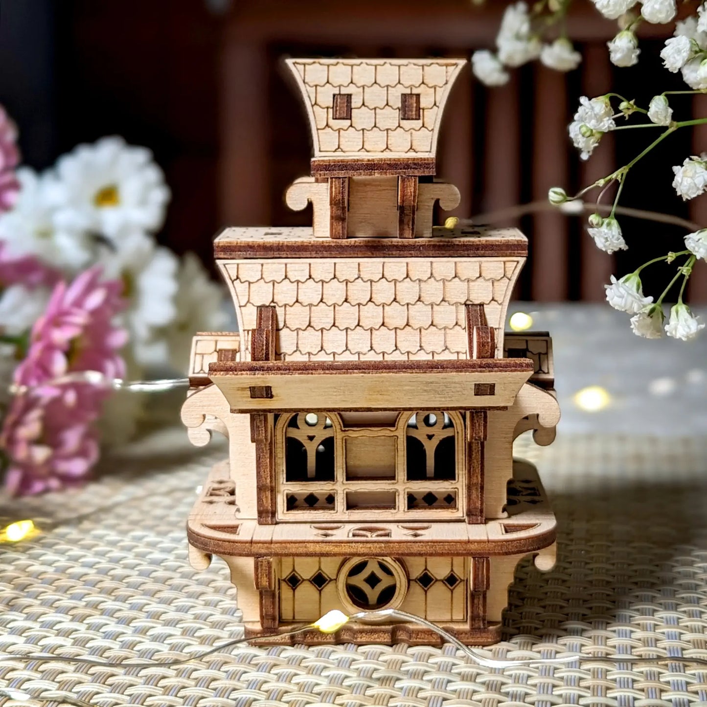 Back view of a laser cut plywood fairy house. Shows intricate roof shingle design and delicate wooden wall architecture.