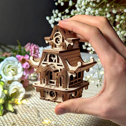 Hand holding a small laser cut plywood fairy house to show scale. Detailed wooden miniature home for collectors.