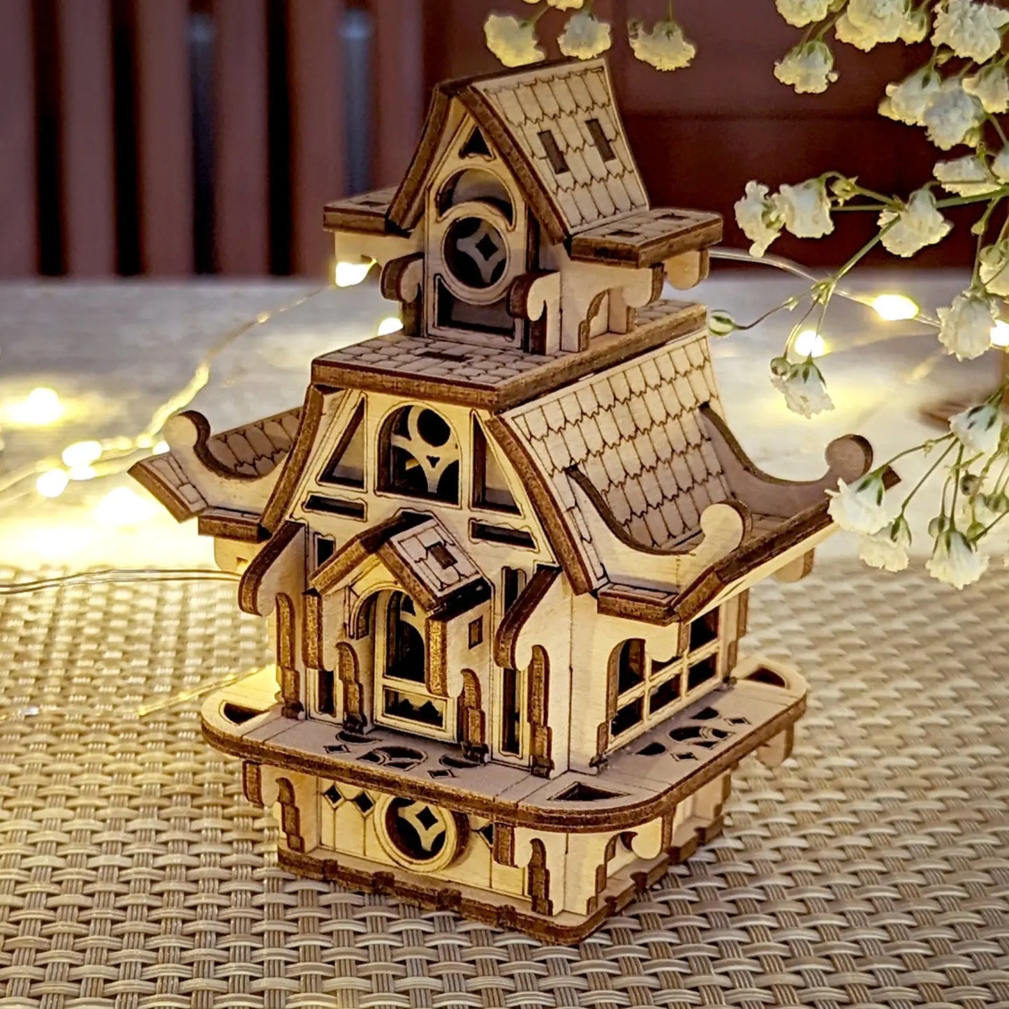 Charming laser cut plywood fairy house on a textured surface. Perfect miniature home with intricate wooden details.