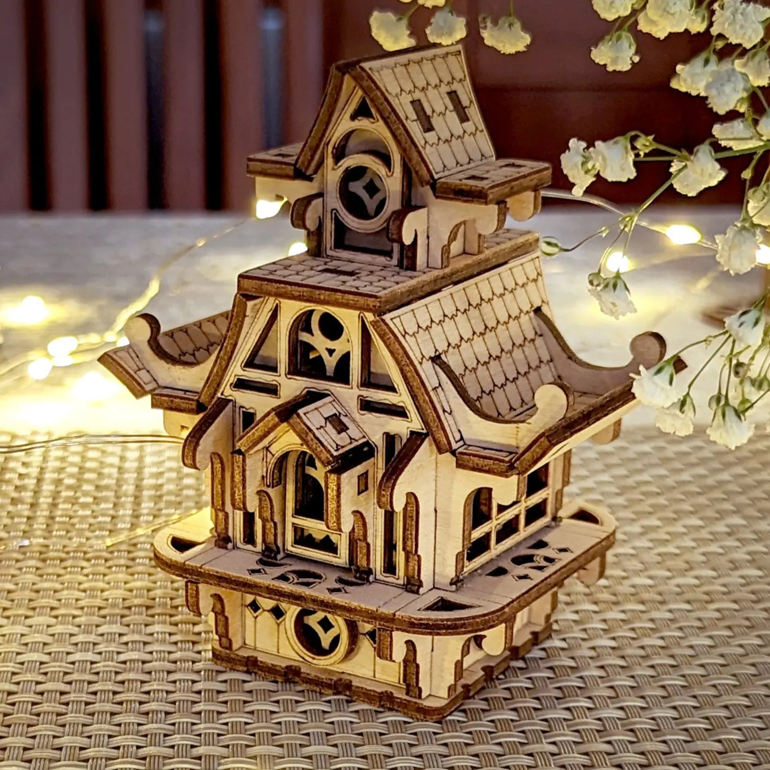 Charming laser cut plywood fairy house on a textured surface. Perfect miniature home with intricate wooden details.