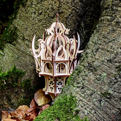 Close-up view of a laser cut plywood elf tower with miniature warriors carved on sides, nestled against a tree trunk.