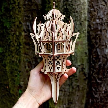 Detailed close-up of a laser cut plywood fantasy tower held in a male hand, showing fine engravings and layered design.