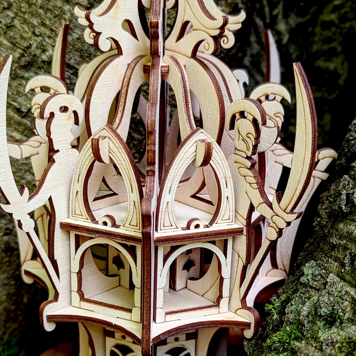 Extreme close-up of a laser cut plywood elven tower lantern showing layered arches and precise laser-burned dark lines.