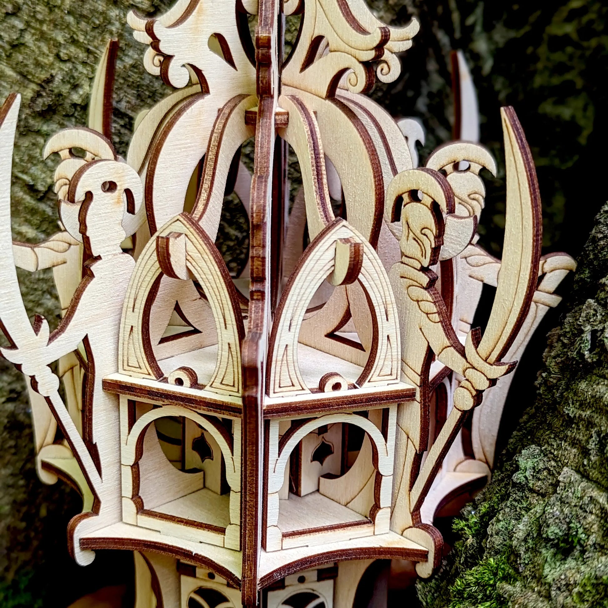 Extreme close-up of a laser cut plywood elven tower lantern showing layered arches and precise laser-burned dark lines.