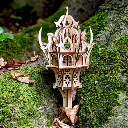 Tight close-up of a laser cut plywood elven structure with tiny guards holding swords, placed on vibrant green moss.