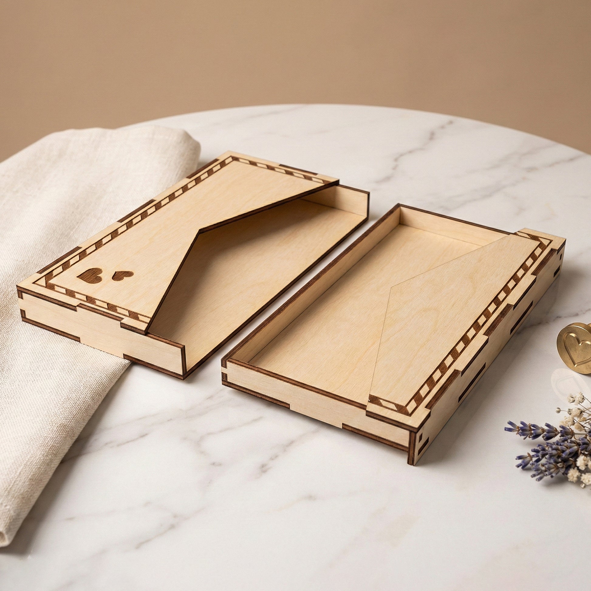 Two halves of an open laser cut plywood envelope lying flat on a white table. The interior reveals a hollow compartment for holding a gift card or cash. A linen cloth and sprig of lavender sit nearby, showing the item's small scale.
