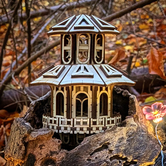 An atmospheric shot of a miniature fairy pagoda house made from laser cut plywood, beautifully glowing inside a tree log