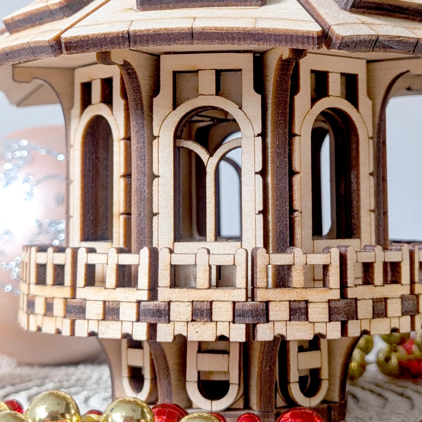 Macro close up focusing on the geometric balcony railing and miniature arched windows of a laser cut plywood fairy house