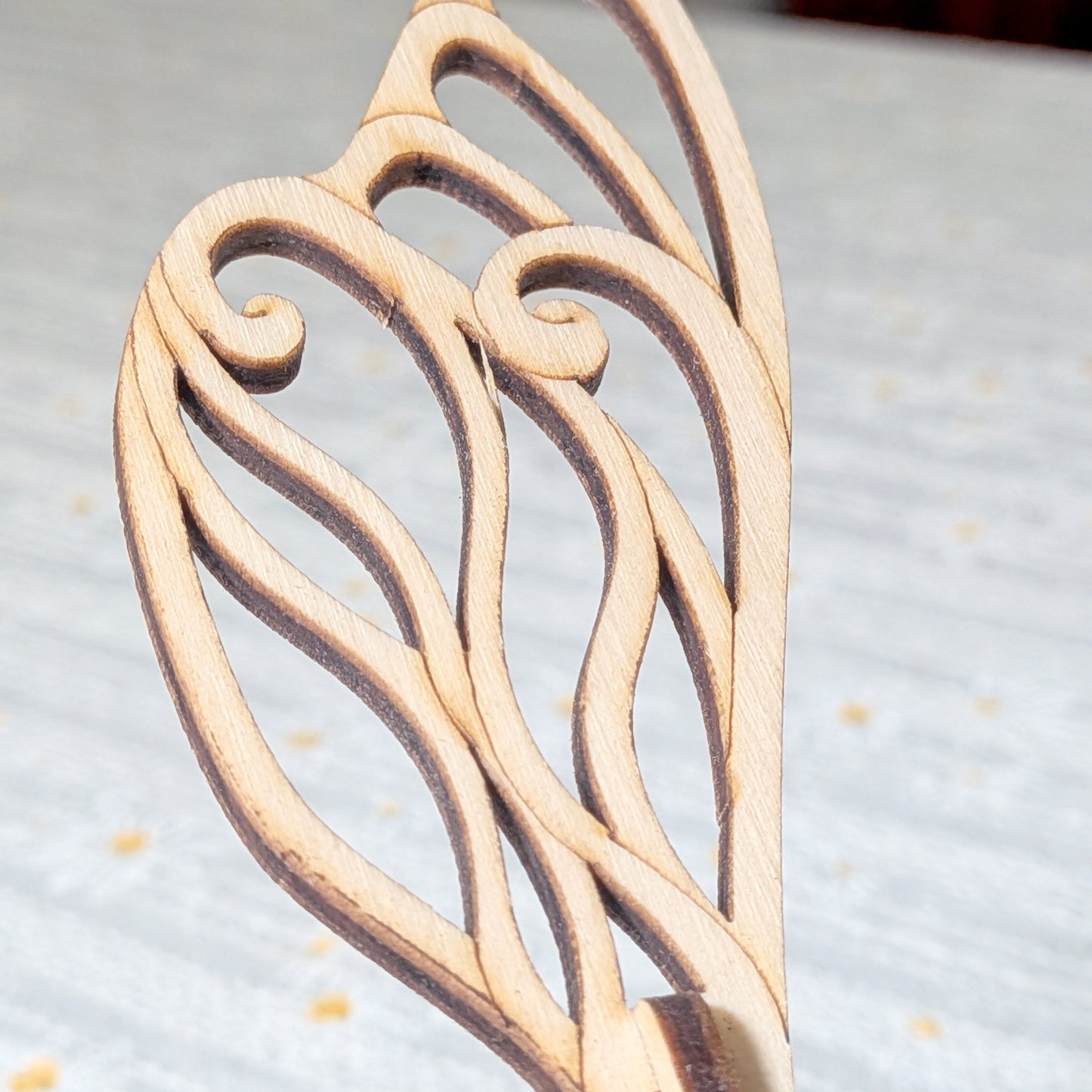 Detailed view of a fairy bee wing made from laser cut plywood, featuring elegant curved lines and smooth wooden finish