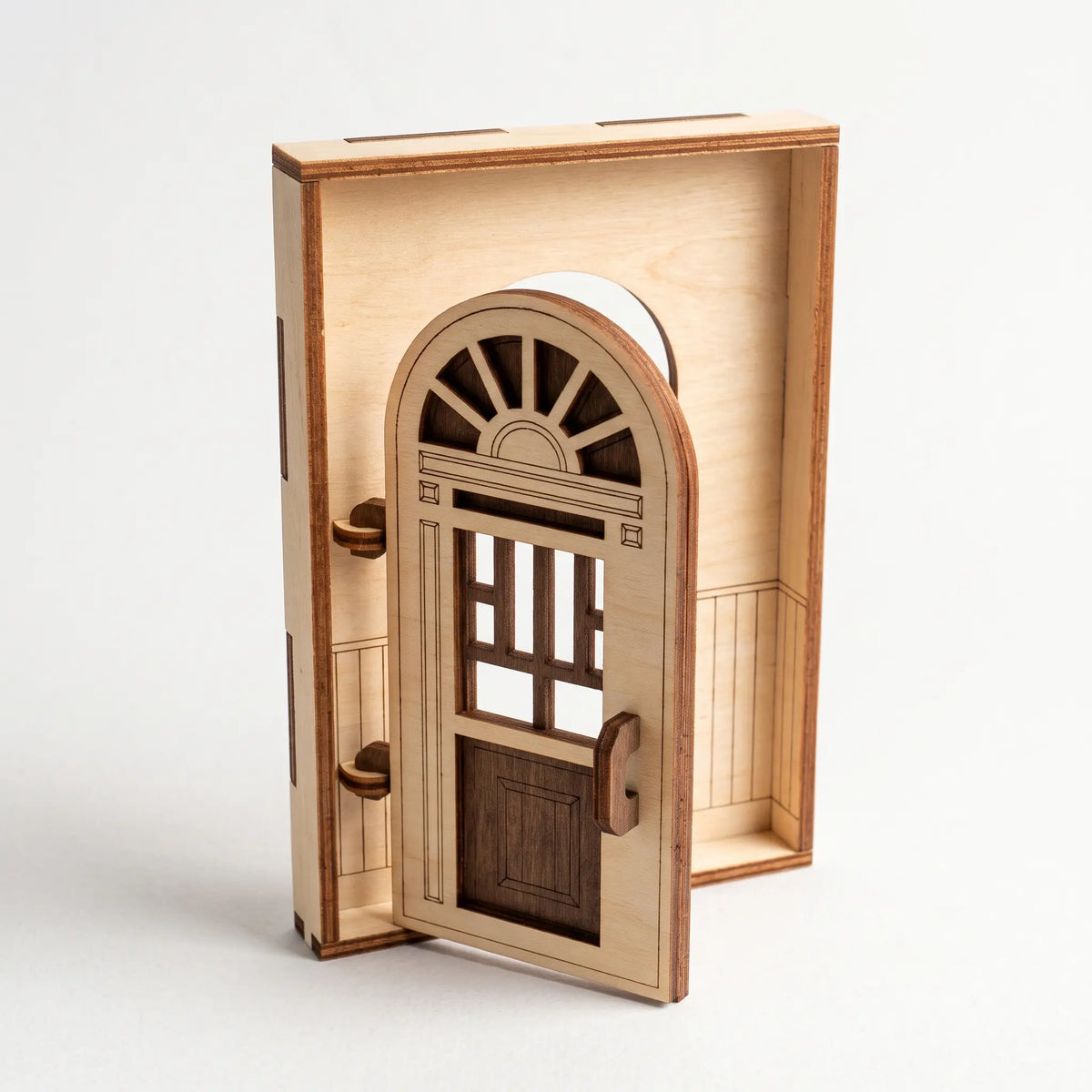 Open architectural laser cut plywood fairy door model with arched transom window and paneled interior on white background.