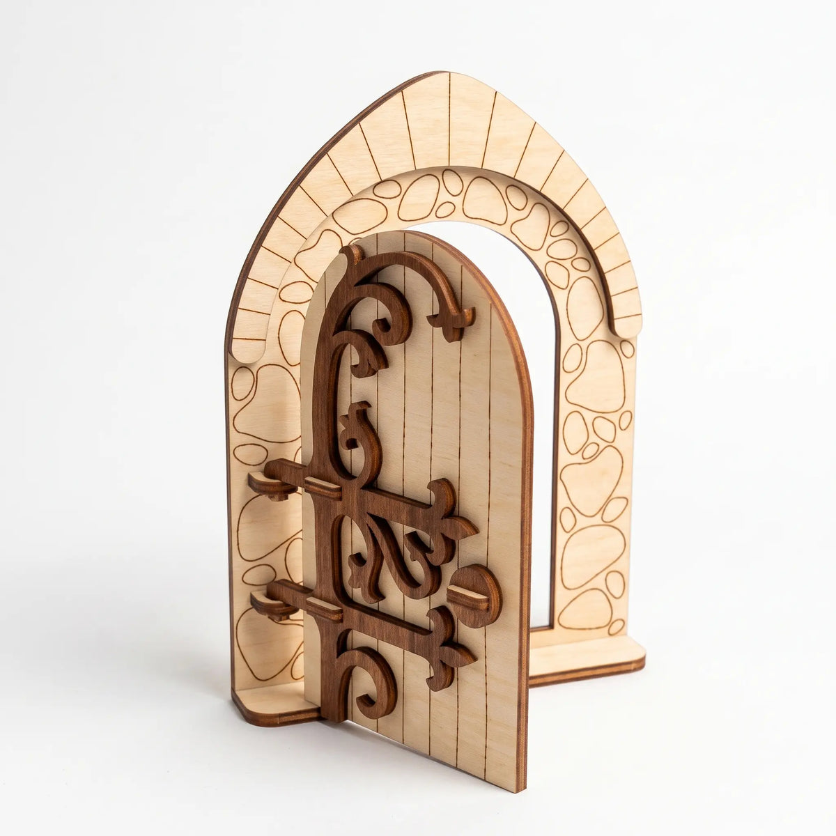 Medieval style arched laser cut plywood fairy door model featuring ornate wooden scrollwork hinges against a plain white backdrop.