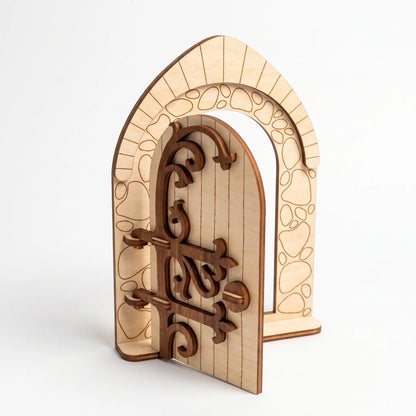 Medieval style arched laser cut plywood fairy door model featuring ornate wooden scrollwork hinges against a plain white backdrop.