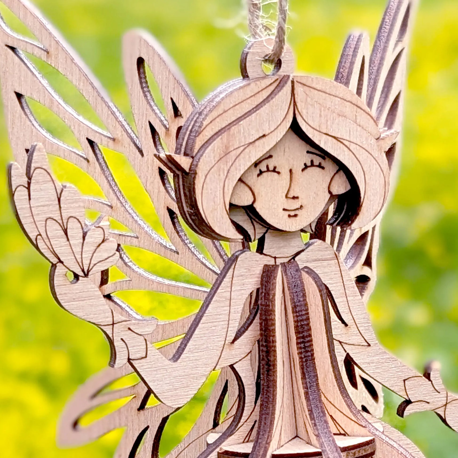 Wooden laser cut fairy ornament with a blurred green background