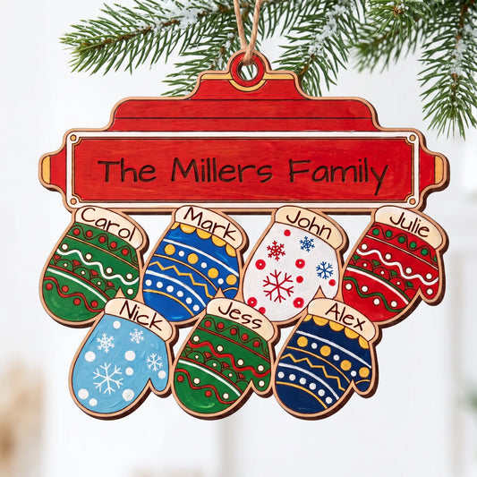 Painted laser cut plywood Christmas family ornament with seven colorful name mittens hanging on snow-dusted pine branch.