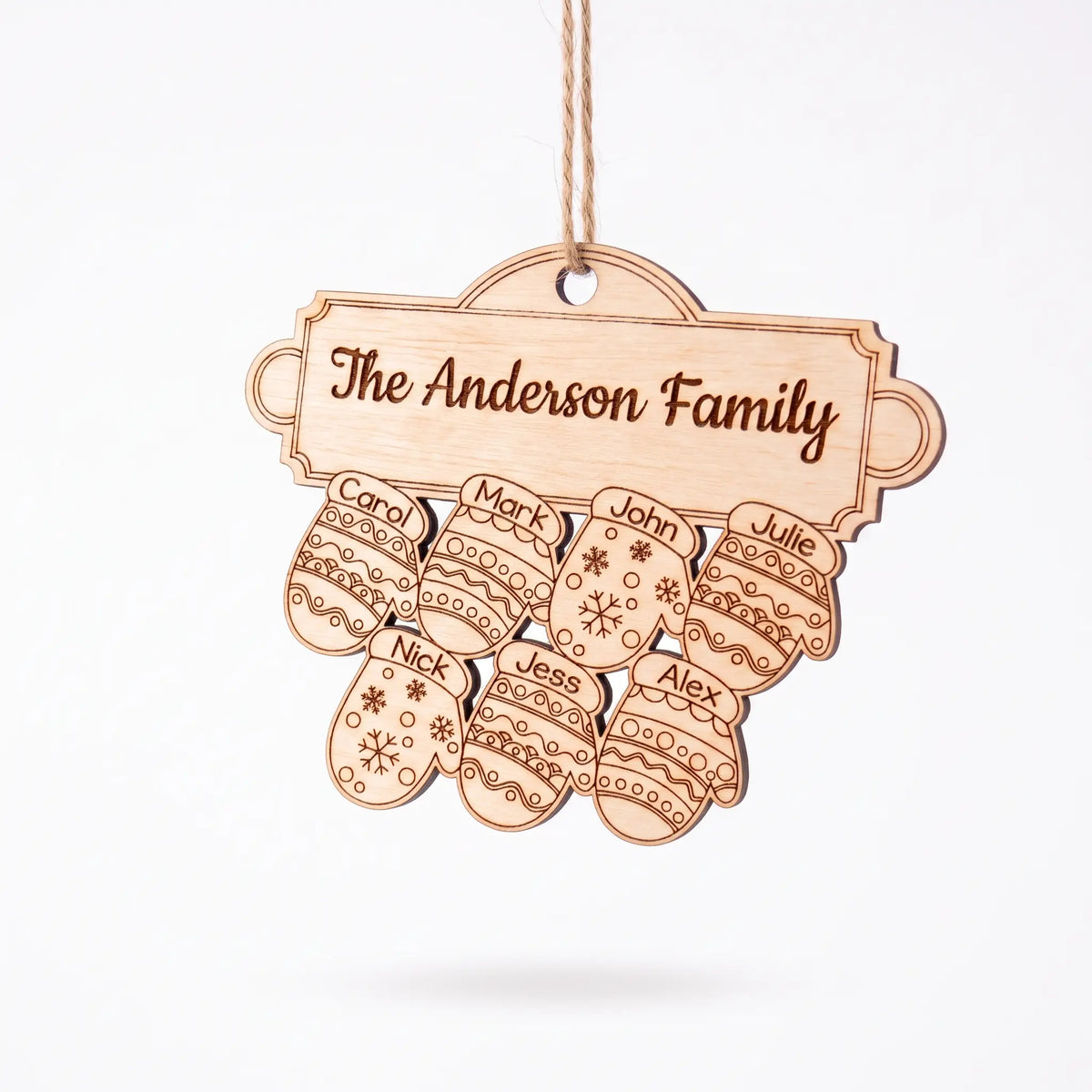 Angle view of natural laser cut plywood family mitten ornament with seven engraved names hanging on plain white background.