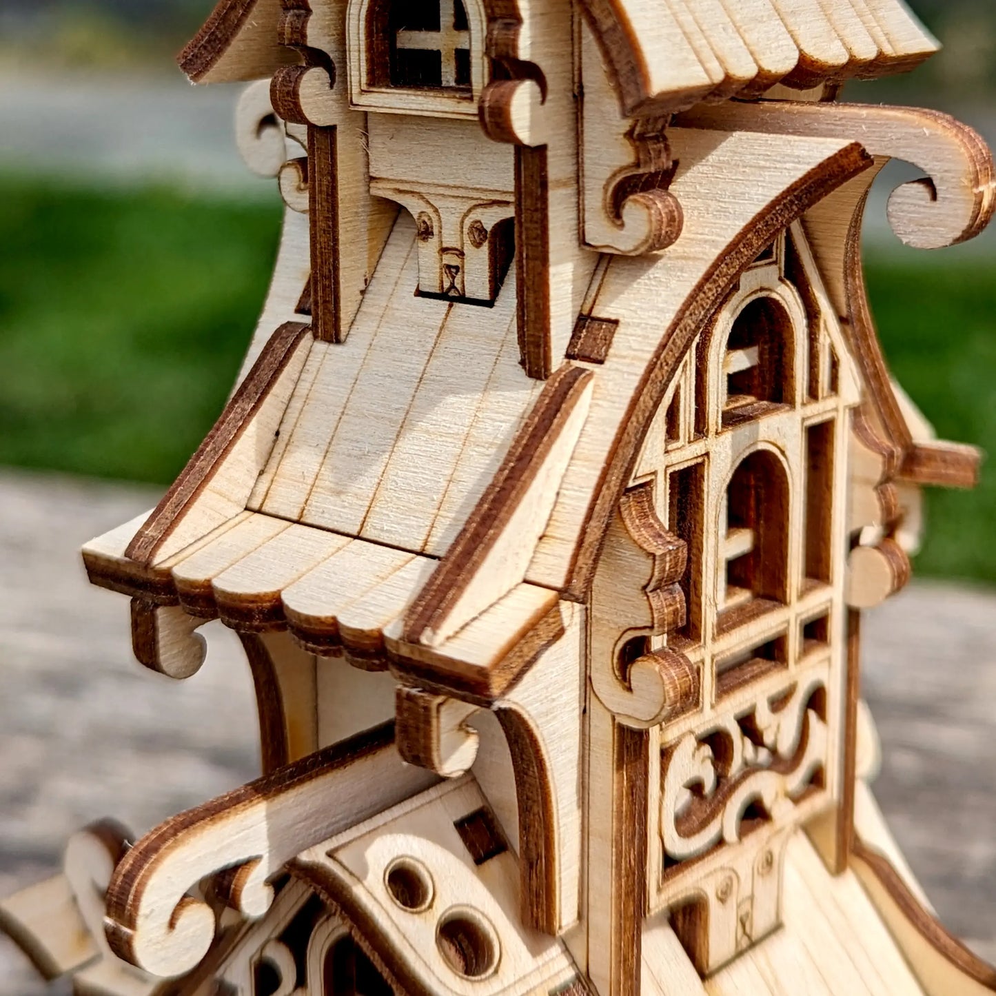 Macro shot focusing on intricate wheel spokes and window frames of a laser cut plywood fairytale carriage model.
