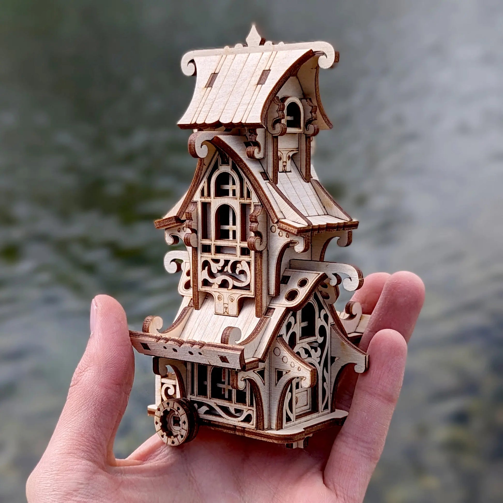 Decorative laser cut plywood camper van miniature nestled inside a hollow tree trunk root with natural soft bokeh.