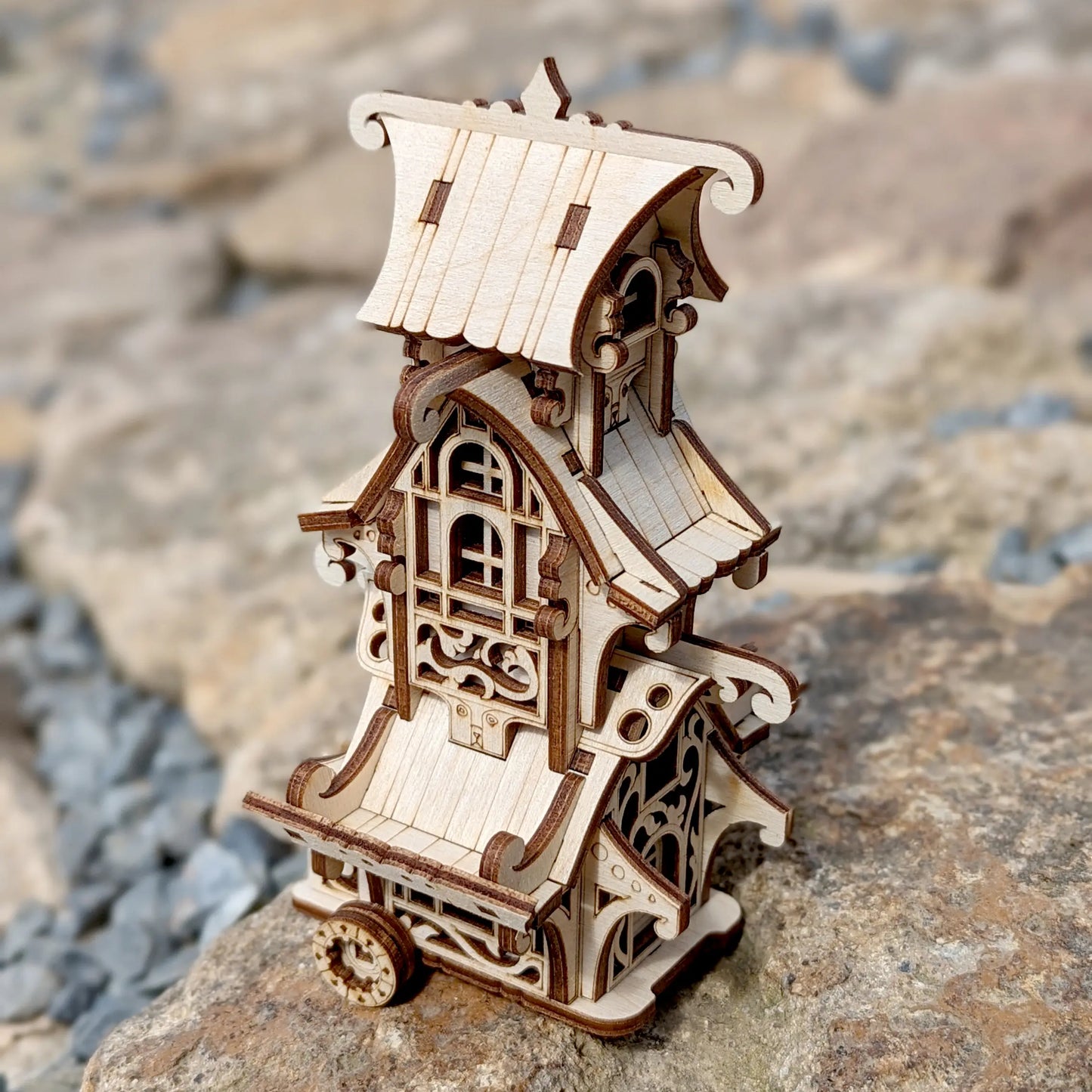 Miniature fantasy caravan wagon made of laser cut plywood with detailed stairs and flower box on a white background.