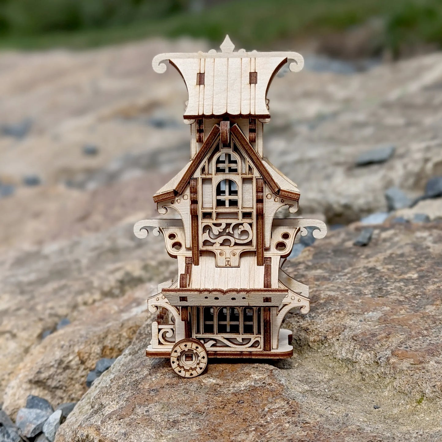 Miniature fantasy caravan wagon made of laser cut plywood with detailed stairs and flower box on a white background.