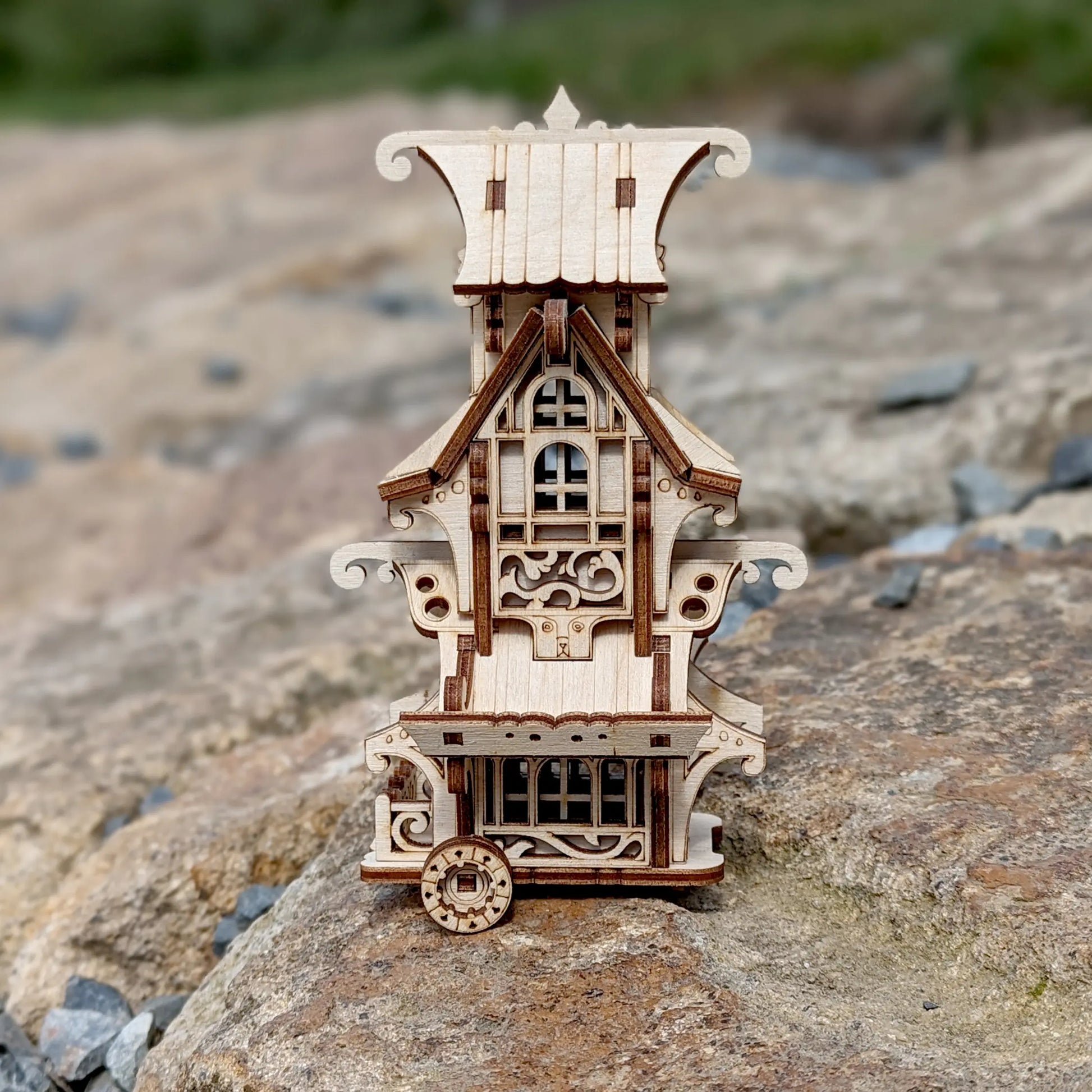 Miniature fantasy caravan wagon made of laser cut plywood with detailed stairs and flower box on a white background.