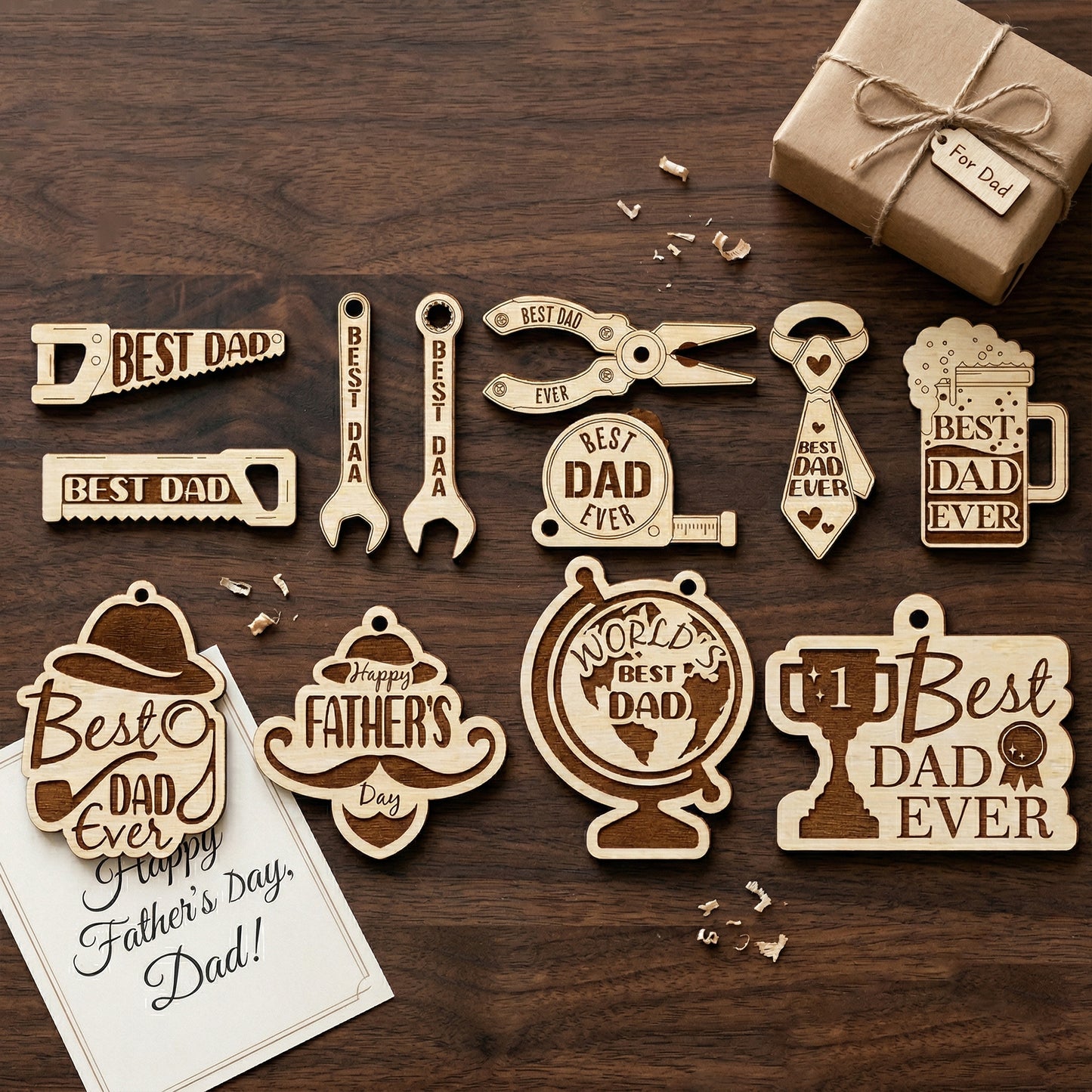 Tool-themed wooden Father's Day charms arranged on a dark tabletop. The set includes a saw, pliers, wrenches, and a trophy, each made of laser-cut plywood with detailed engravings. A small brown paper gift box tied with twine sits in the corner.