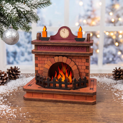 Painted laser cut plywood holiday fireplace diorama with burning fire and mantle clock on snowy table near winter window.