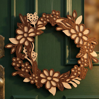 A handcrafted layered laser-cut plywood floral wreath hanging on a dark green door. The spring-themed design features intricate daisies and leaf patterns in contrasting light and dark wood tones. Warm natural light highlights the wood grain and the 3D depth of the piece.
