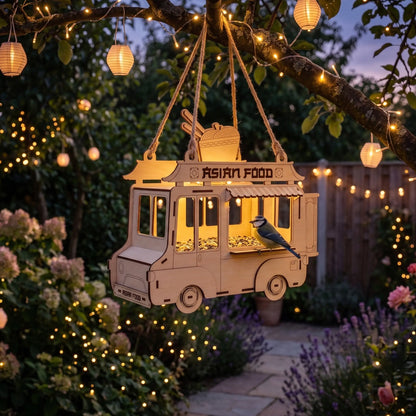 Decorative Asian food truck birdhouse hanging from a tree with string lights in a garden.