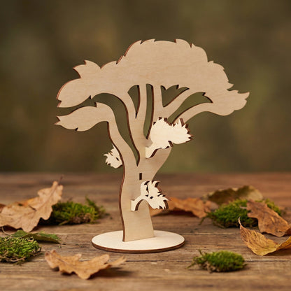 Close-up of a spreading oak tree model made of laser cut plywood. The tree features precise cutouts and a sturdy round base. Its minimalist design highlights the warm, natural texture of the wood against a soft green background