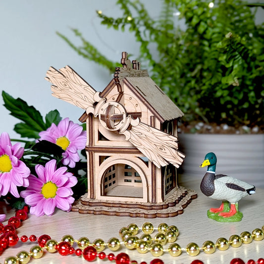 Beautiful product photo of a miniature forest windmill puzzle made from laser cut plywood, styled with bright pink flowers.