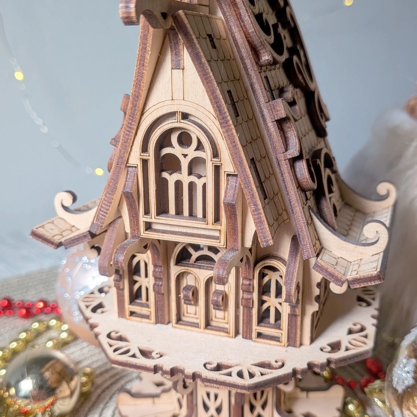 Close up view of a laser cut plywood elf cottage facade showcasing miniature arched windows, doors, and balconies.