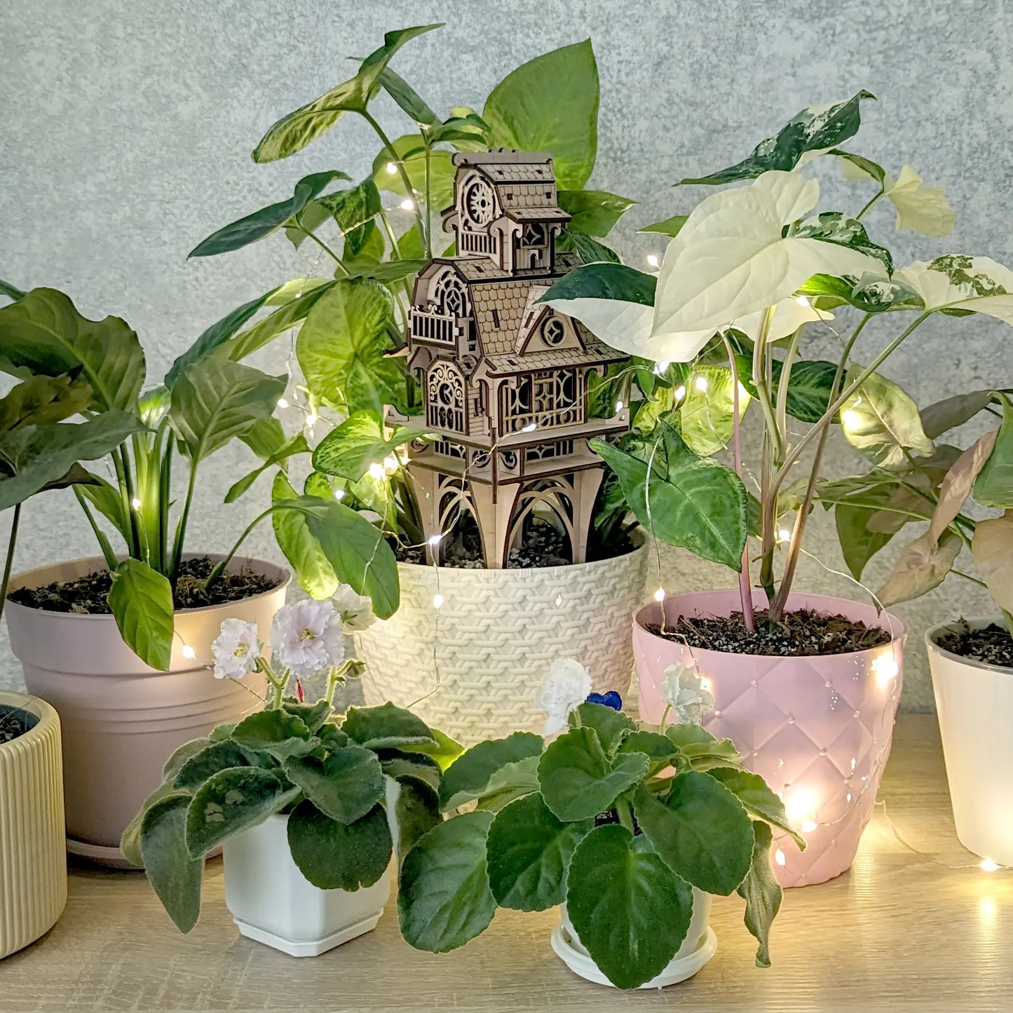 Eye-level studio shot of the laser cut plywood fairy home centerpiece, beautifully framed by bright house plants.