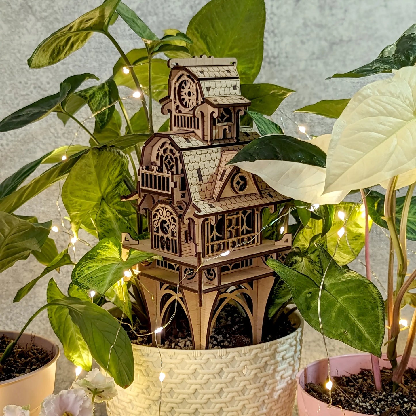 Elegant vertical presentation of the 3D laser cut plywood fairy castle structure, surrounded by green plant leaves.