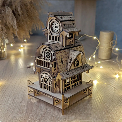 High-angle shot of the assembled laser cut plywood wizard cabin model on a table, decorated with bright fairy lights.