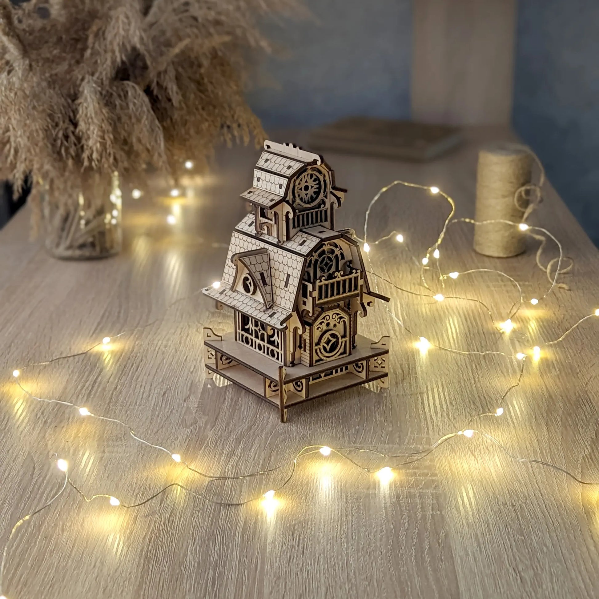 High-angle shot of the laser cut plywood wizard cottage on a desk, encircled by glowing warm fairy string lights.