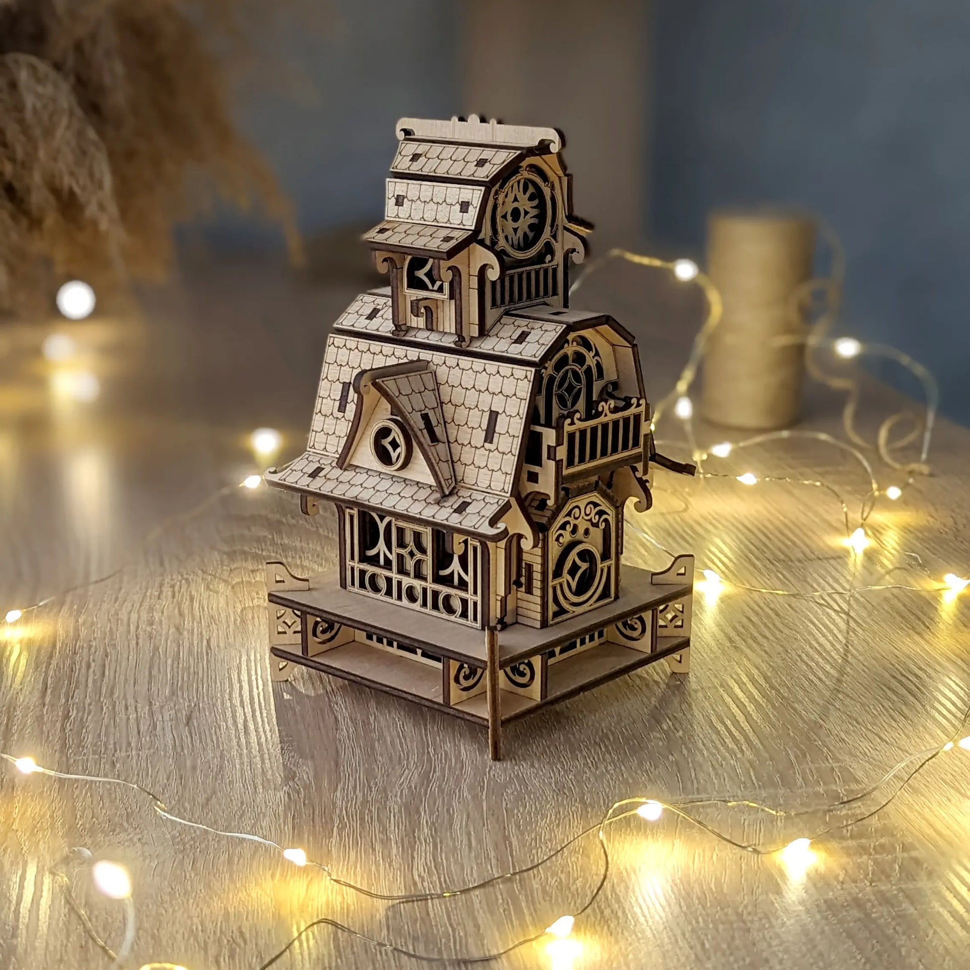 Three-quarter overview of the assembled laser cut plywood tabletop tower puzzle, styled with coiled fairy lights.