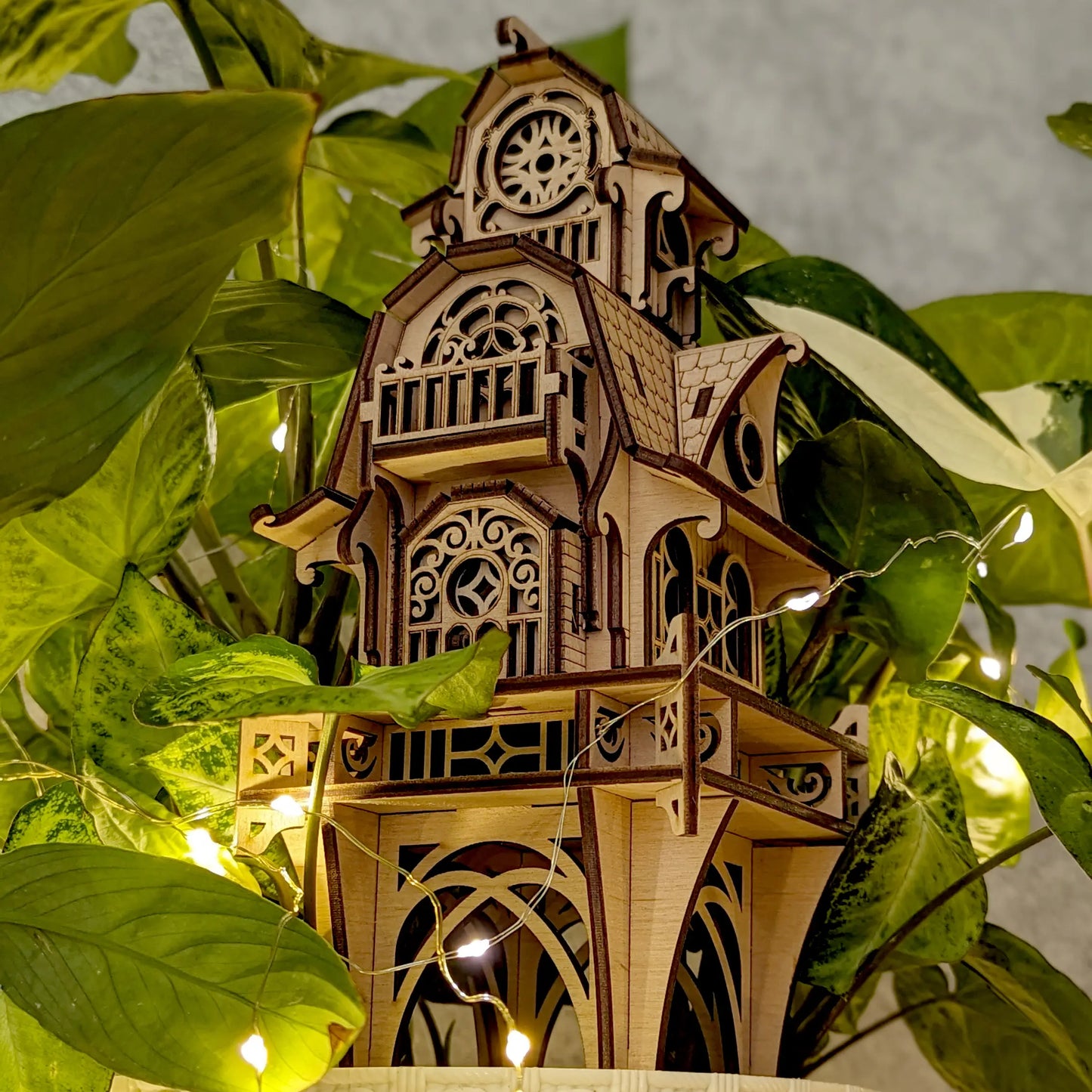 Low-angle architectural macro shot of the laser cut plywood tower base, decorated with delicate glowing wire lights.
