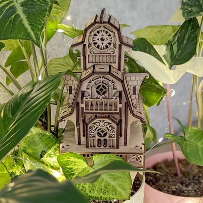 Straight symmetrical front view of the laser cut plywood witch house stake standing upright inside a flowerpot.