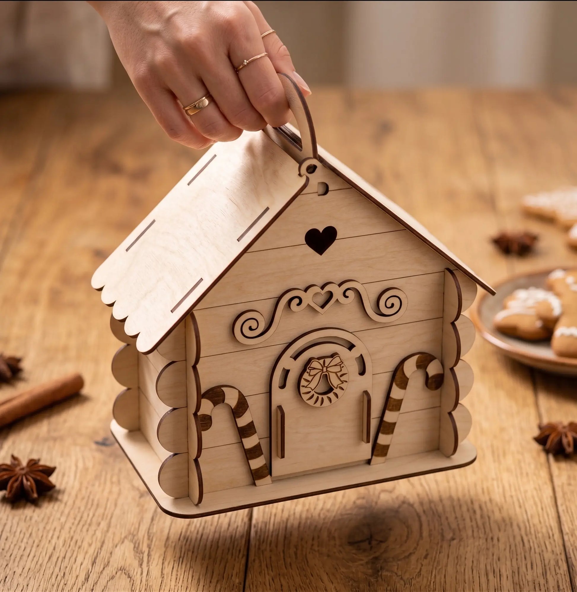 Wooden house-shaped box with decorative elements on a wooden table.