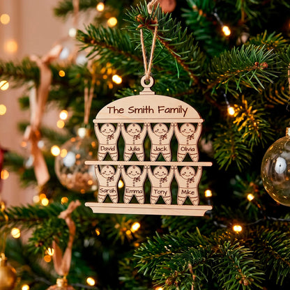 Two-tiered gingerbread family Christmas ornament made of laser cut plywood, hanging on a lit tree branch.