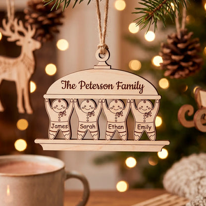 Personalized laser cut plywood Christmas ornament shaped like a gingerbread family of four hanging near a warm mug.