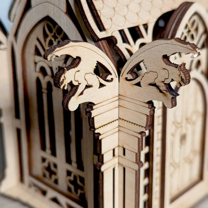 A detailed macro photo focusing on the two tiny engraved gargoyles on a corner pillar made of layered laser cut plywood.