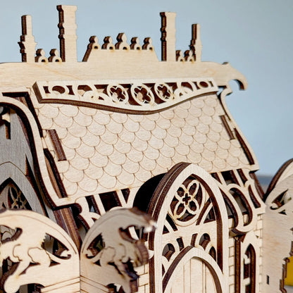 A macro close-up focusing on the finely engraved scale tile patterns on the roof of a miniature laser cut plywood house.