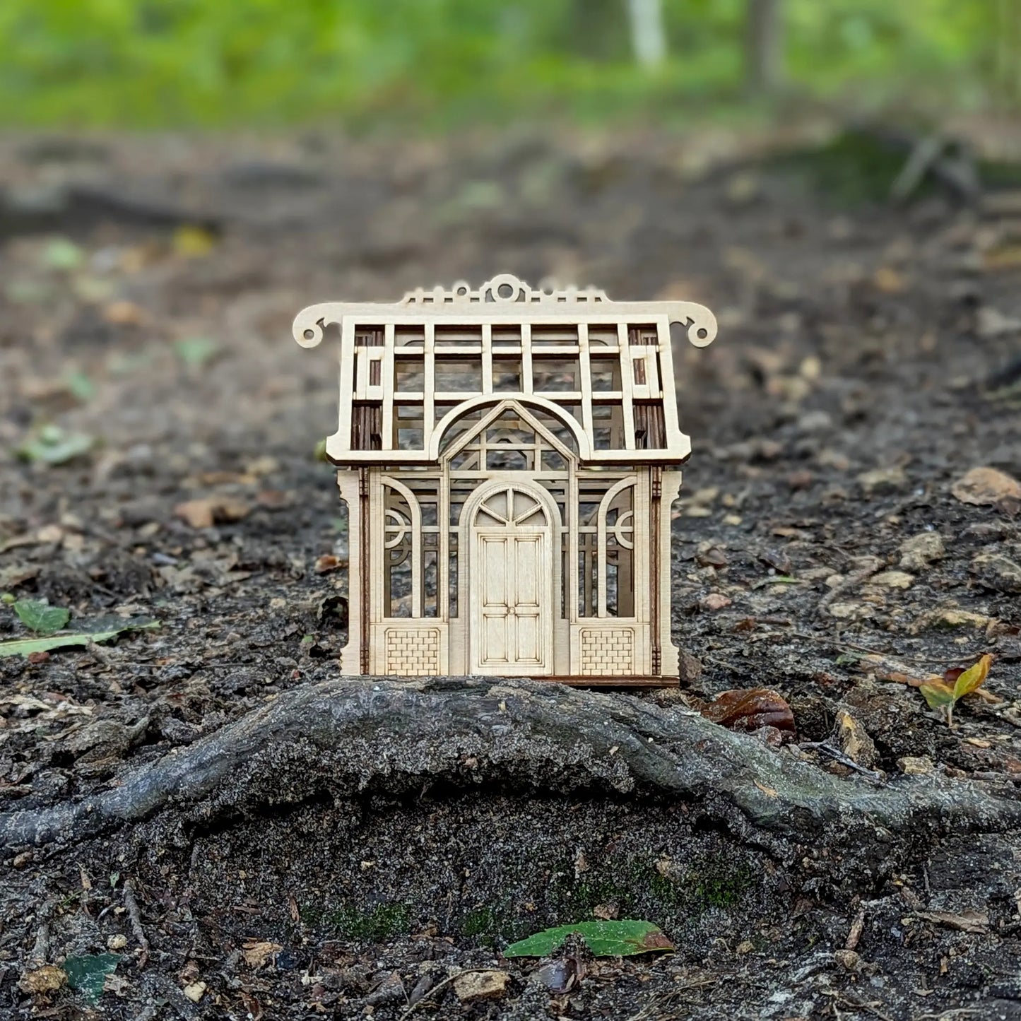 Tighter front perspective view of a charming miniature holiday village greenhouse toy made from layered laser cut plywood.
